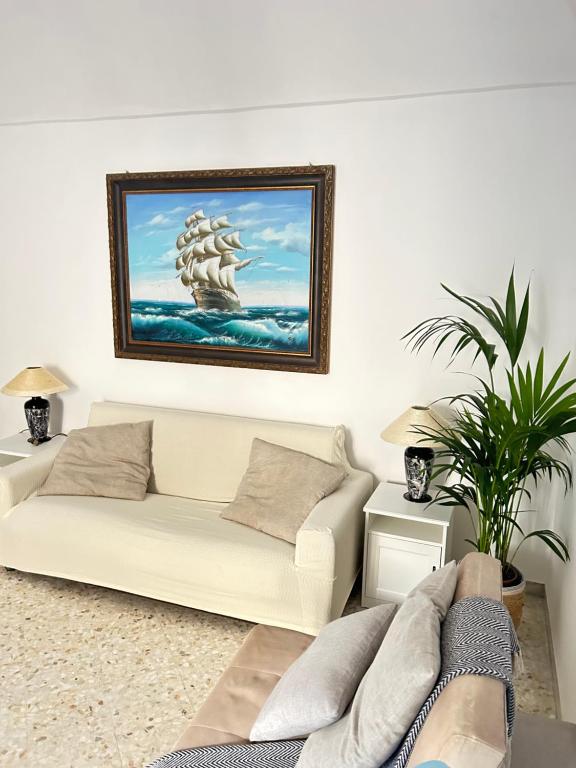 a living room with a white couch and a painting of a ship at DIMORA ELIVA in Monopoli