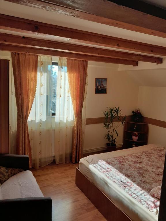 a bedroom with a bed and a window with curtains at Casa Geo in Breaza de Jos