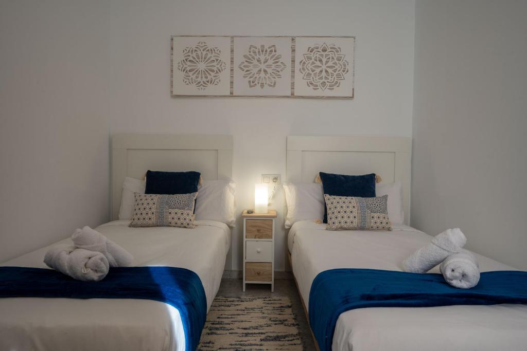 two beds in a room with blue and white at Reina Aixa- Apartamento Centro in Granada