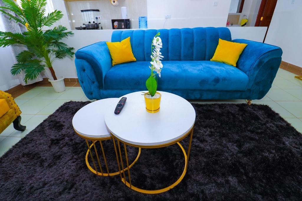 - un salon avec un canapé bleu et une table dans l'établissement Betty's staycation Thika road, à Nairobi