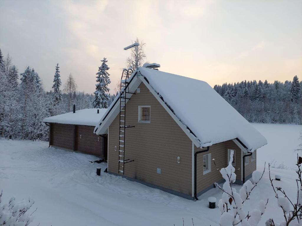 a building with a snow covered roof in the snow at Mökki ulkoporealtaalla in Uurainen