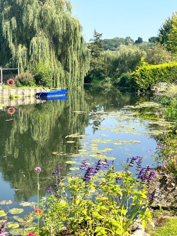 a blue boat in a river with flowers at Appleby Barn in Lacock