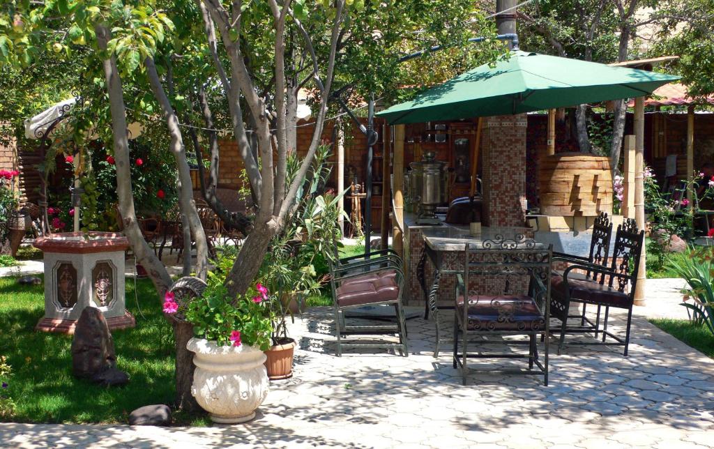 eine Terrasse mit einem Tisch, Stühlen und einem Sonnenschirm in der Unterkunft Art Hotel Al Hayat in Kaji-Say