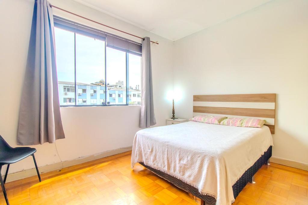 a bedroom with a bed and a large window at Apto com Wi Fi proximo ao centro Porto Alegre RS in Porto Alegre
