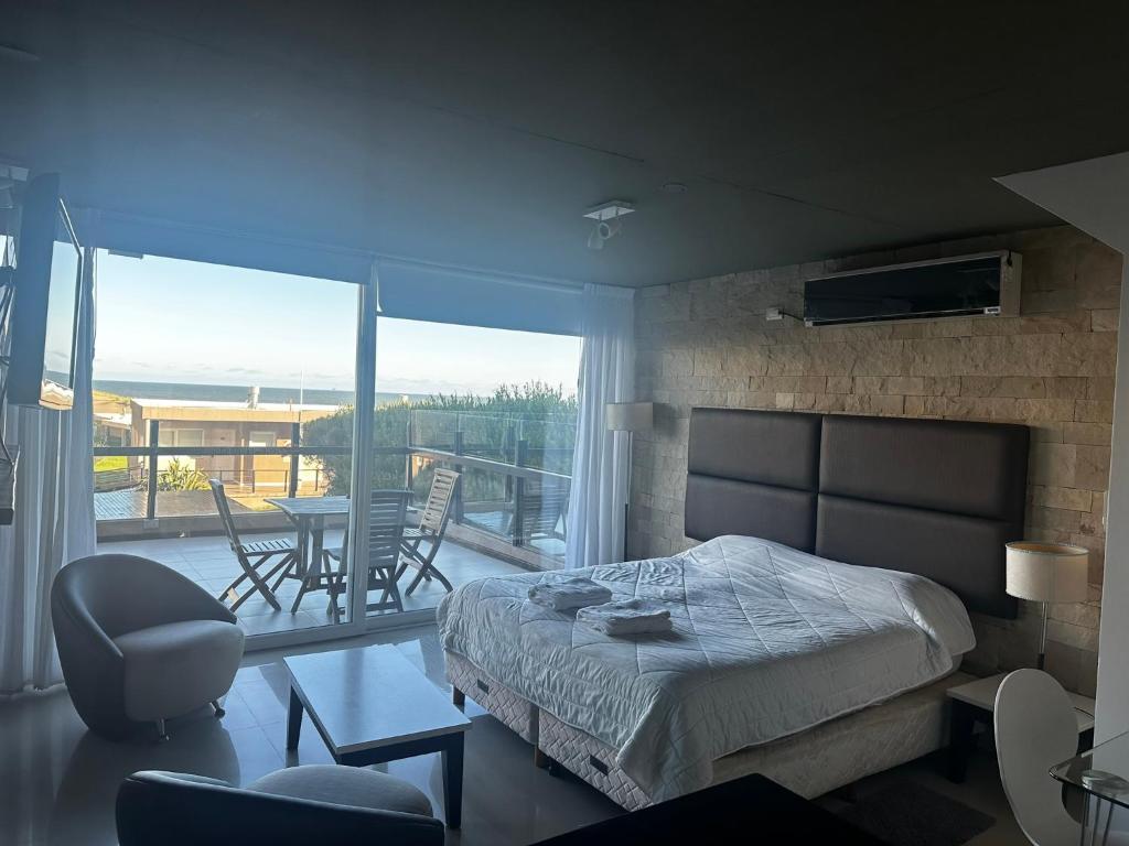 Un dormitorio con una cama y un balcón con mesa y sillas. en Linda Bay Spa Apartments, en Mar de las Pampas