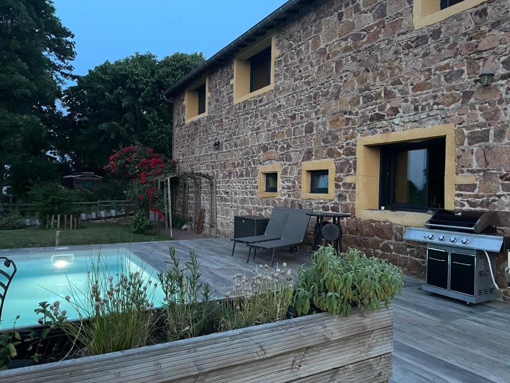 ein Steinhaus mit einem Pool und einer Terrasse in der Unterkunft La Grange aux hirondelles - appartement complet et indépendant in Commelle-Vernay