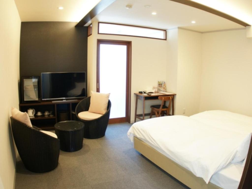 una camera con un letto e due sedie e una televisione di Kanazawa Station Hotel - Vacation STAY 36354v a Kanazawa