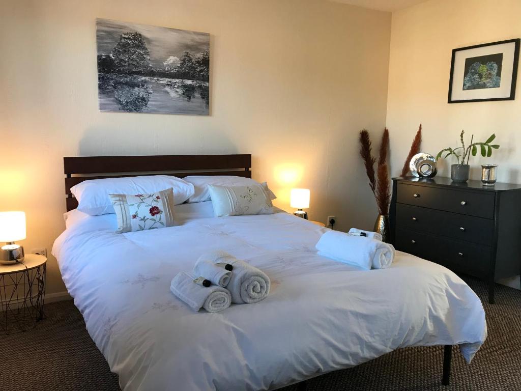 a bedroom with a large white bed with towels on it at Lavender Cottage in Thirsk