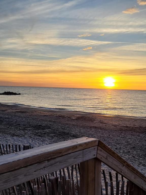a sunset on the beach with a wooden bench at Tahiti Beach, T2 à la mer, piscine, terrasse et parking in Frontignan