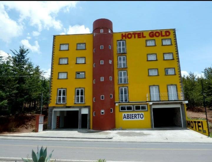 een geel hotelgebouw met een gouden bordje erop bij HOTEL GOLD in El Oro de Hidalgo