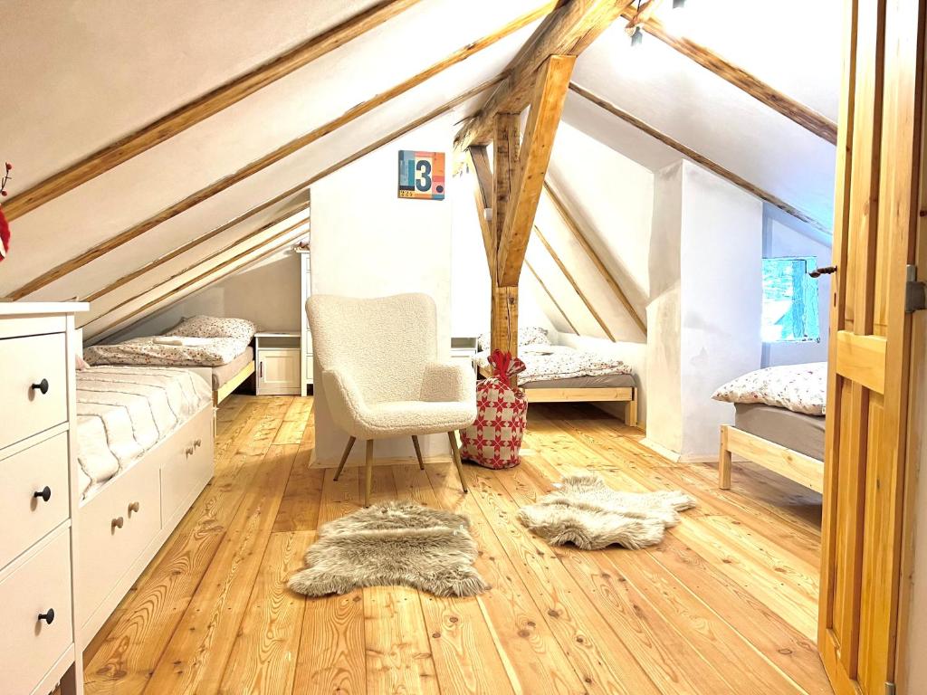 a attic bedroom with two beds and a chair at Santova roubenka in Štramberk