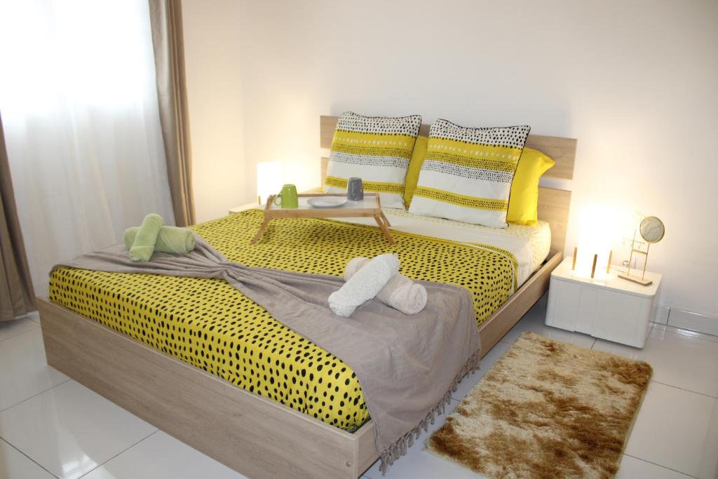 een slaapkamer met een groot bed met gele lakens en kussens bij L'Awara - paisible et chaleureux in Cabassou