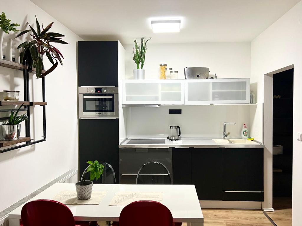 a kitchen with white and black cabinets and a table at Apartment Brno- BBQ terrace in Husovice