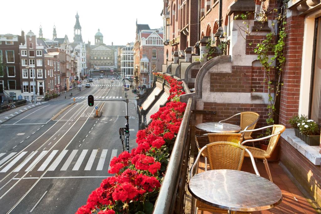 een balkon met tafels en bloemen in een stadsstraat bij Di-Ann City Centre Hotel in Amsterdam