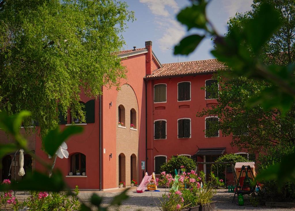 Un bâtiment rouge avec des fleurs devant lui dans l'établissement Quadrifoglio Relax, à San Donà di Piave