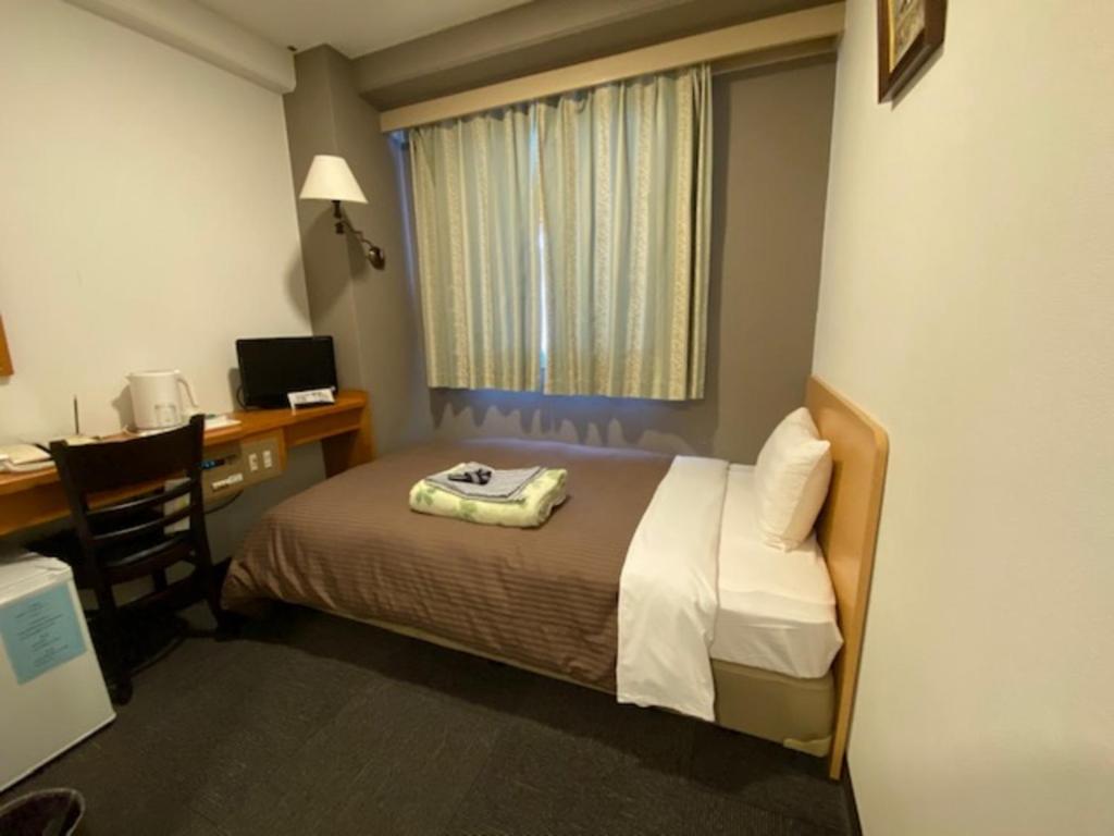 a room with a bed and a desk with a computer at Hotel New Yutaka - Vacation STAY 35249v in Izumi-Sano