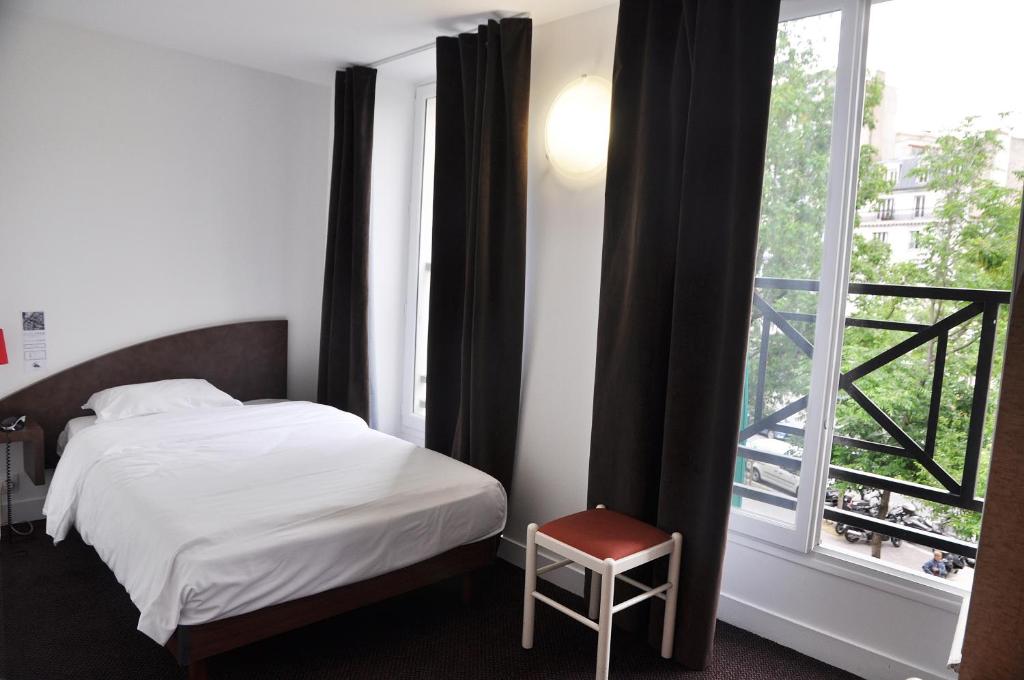 a bedroom with a bed and a large window at Hotel de la Tour in Paris