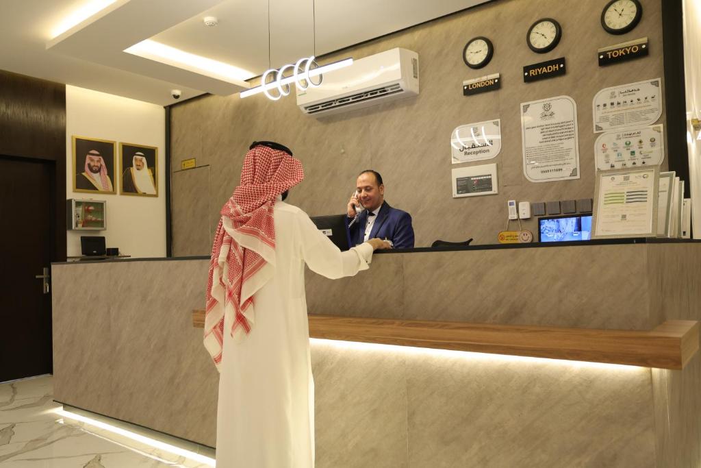 a woman standing in front of a counter with a man at روز نجد للشقق الفندقية in Riyadh