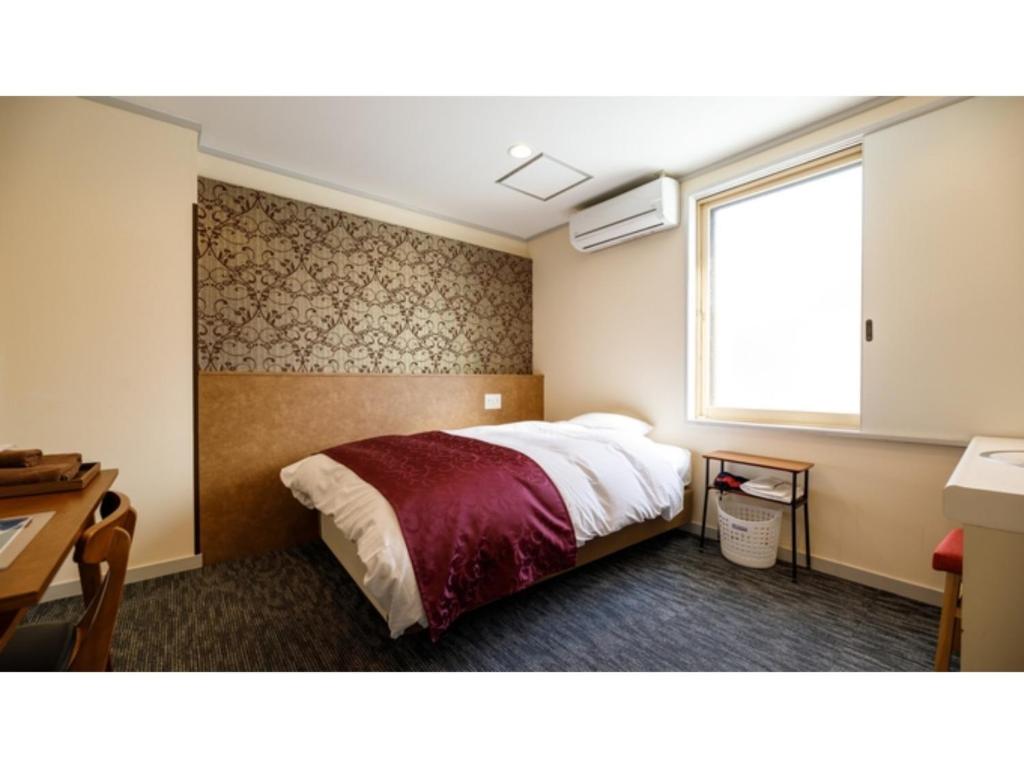 a bedroom with a bed and a window and a desk at Kanazawa Station Hotel - Vacation STAY 36362v in Kanazawa