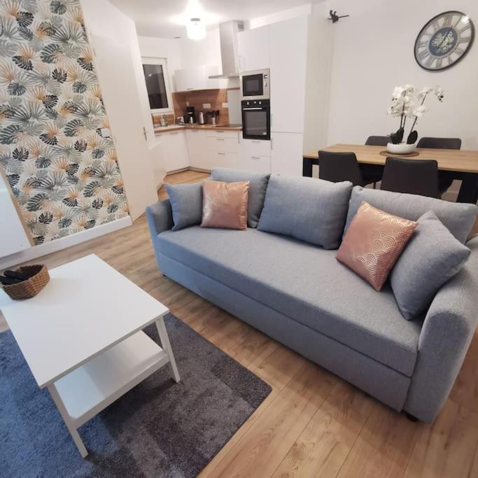 un salon avec un canapé bleu et une cuisine dans l'établissement TYVAC - Maison centre Plougasnou 2 chambres- 4 voyageurs, à Plougasnou