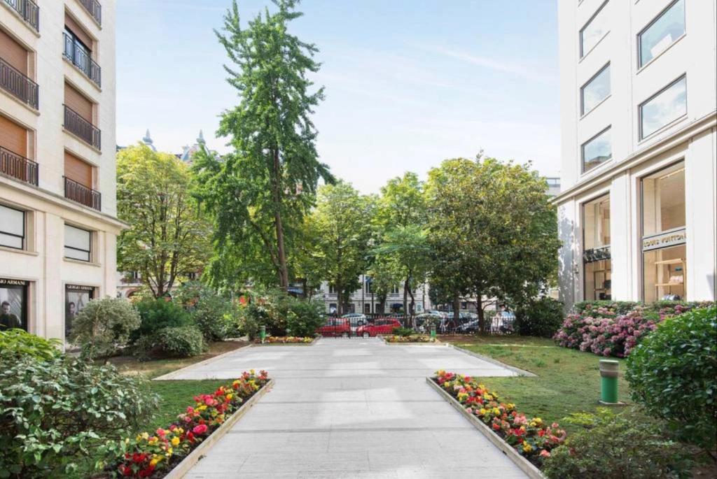 a walkway in a city with flowers and buildings at Avenue Montaigne Paris Bienvenue in Paris