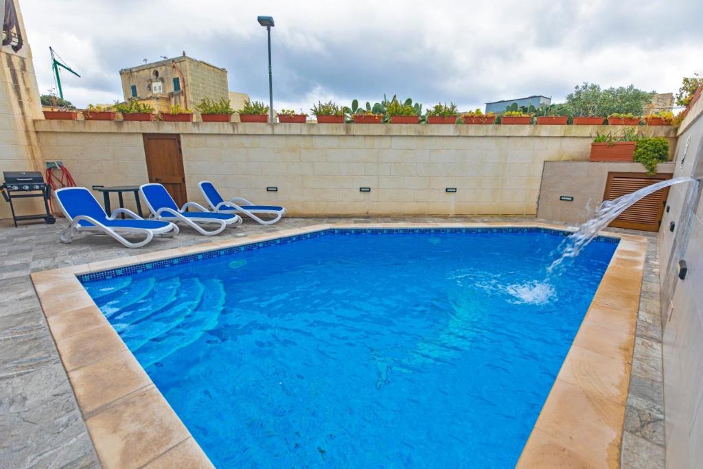 una piscina con sillas y una fuente en 5 Bedroom Holiday Home with Private Pool, en Xewkija