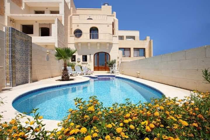 una piscina di fronte a una casa di 3 Bedroom Farmhouse with Private Pool & Views a Għajnsielem