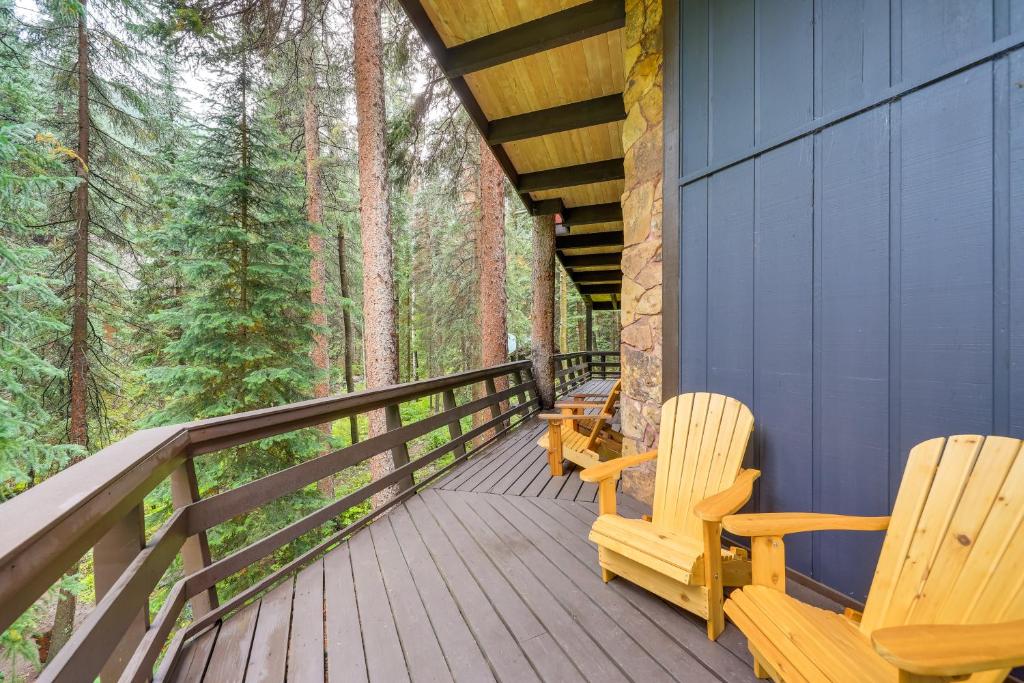 dos sillas de madera sentadas en una terraza en el bosque en Mid-Century Cabin Creekside, Easy Access to i-70, en Dumont
