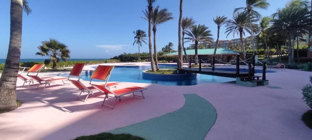 una piscina con sedie, palme e l'oceano di Cimarron Suites Playa Parguito a El Cardón