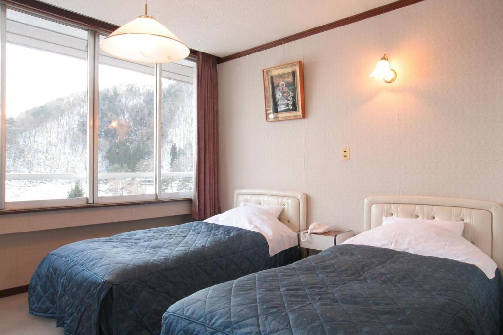 a hotel room with two beds and a window at Yamadaya Hotel in Fujikawaguchiko