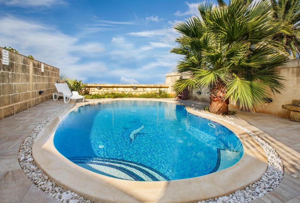 a swimming pool in a yard with a palm tree at 5 Bedroom Farmhouse with Private Pool & Views in Għarb