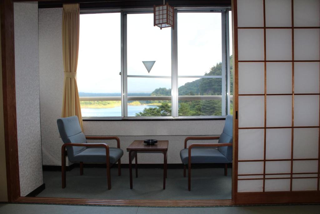 a room with two chairs and a table and a window at Yamadaya Hotel in Fujikawaguchiko