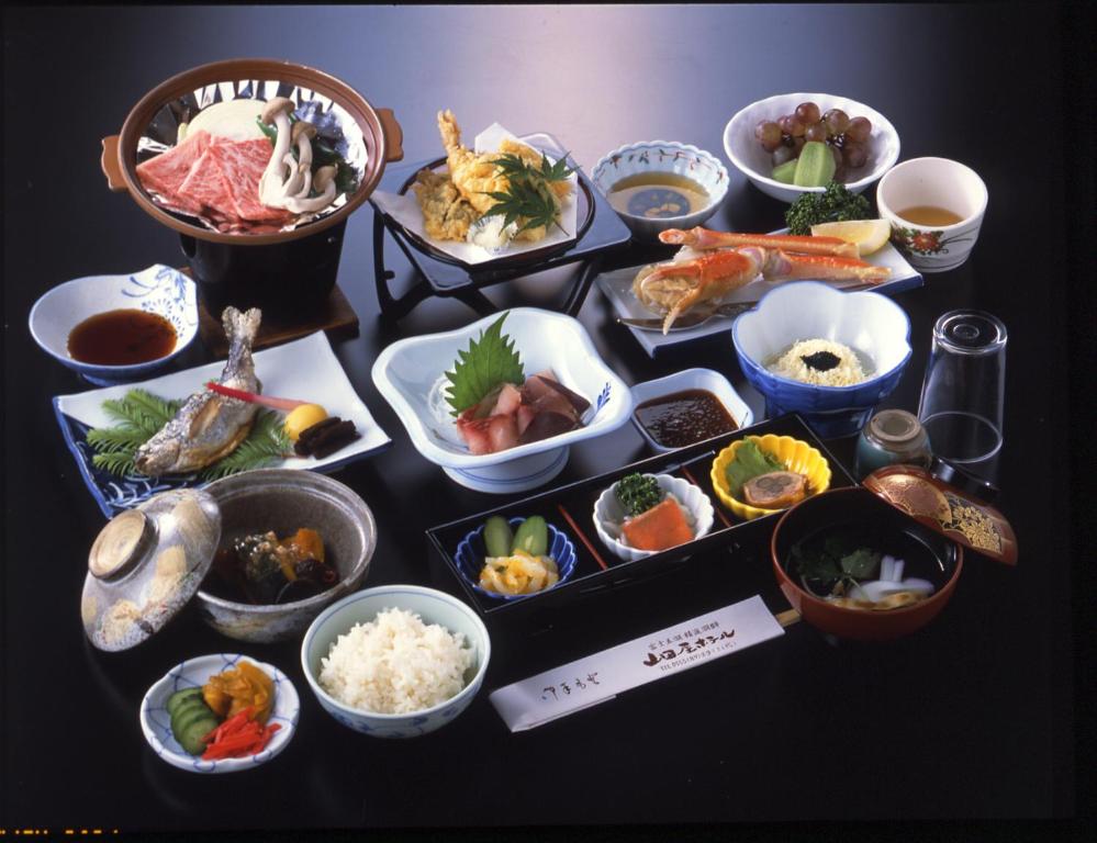 a table topped with different types of food in bowls at Yamadaya Hotel in Fujikawaguchiko