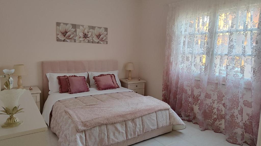 um quarto com uma cama com almofadas cor-de-rosa e uma janela em La Casa di Bonaria em Sestu