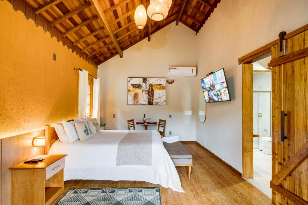 um quarto com uma cama grande e uma mesa em Pousada Jardim Monte Verde em Monte Verde
