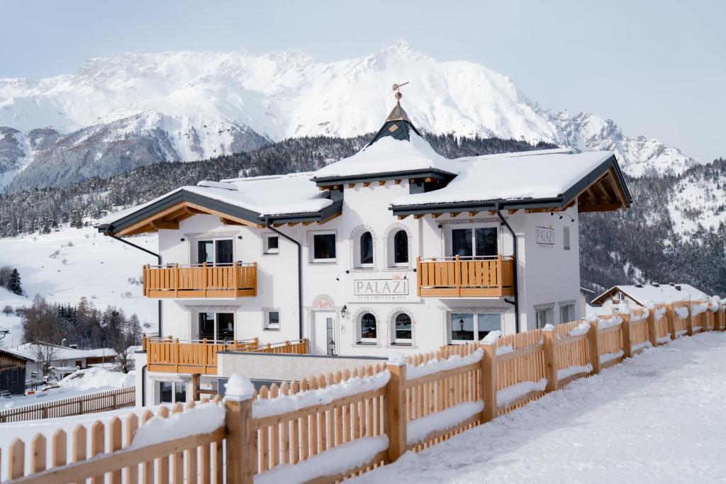 uma casa branca com uma cerca na neve em Palazi Apartments & Spa em Nauders