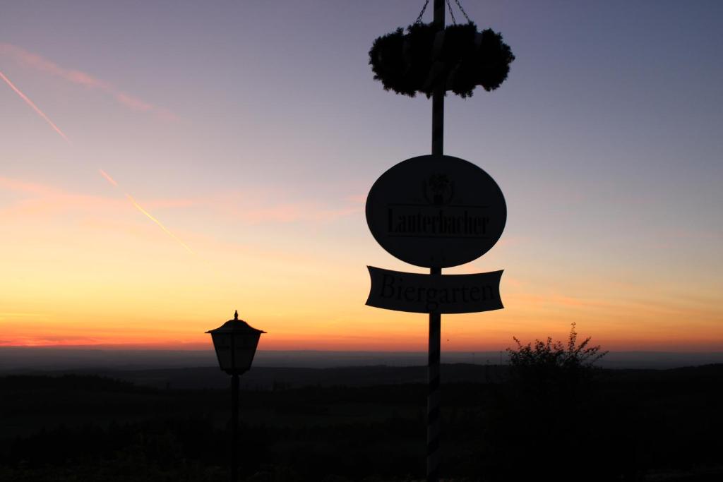 a sign and a street light with the sunset in the background at Berggasthof Hoherodskopf in Schotten