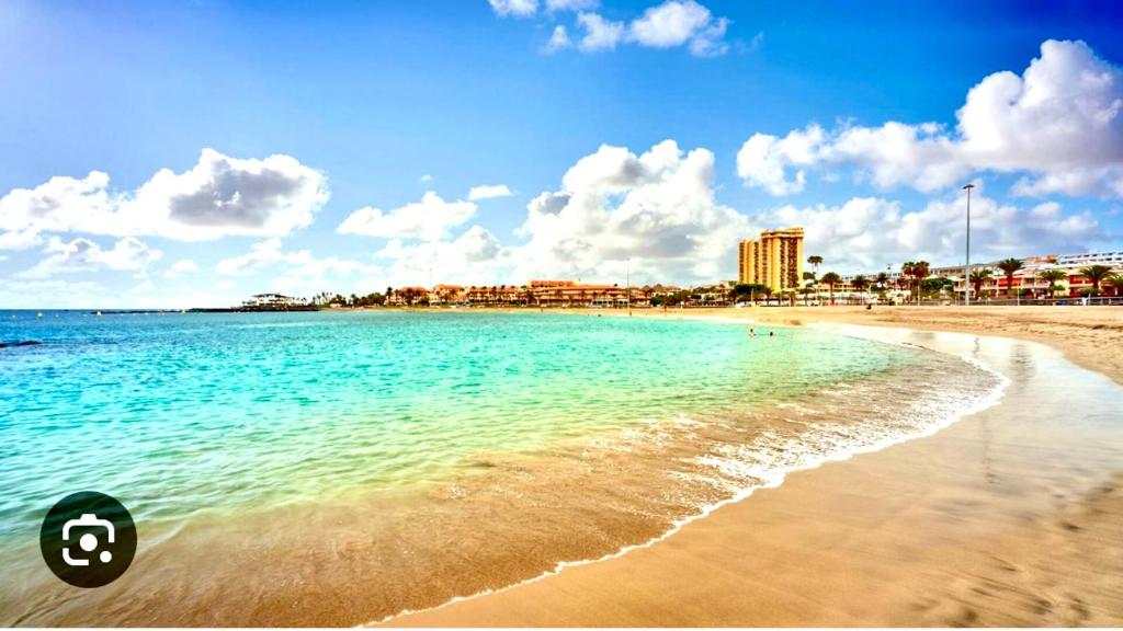 una spiaggia con acqua blu e edifici sullo sfondo di Mara apartment with beautyful oceanview a Playa de las Americas