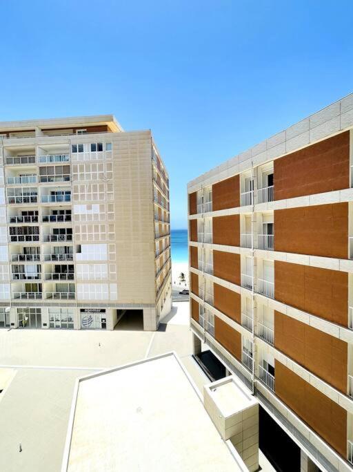 two tall buildings with the ocean in the background at Bliss Apartments T3 - Zita - On The Beach in Mindelo