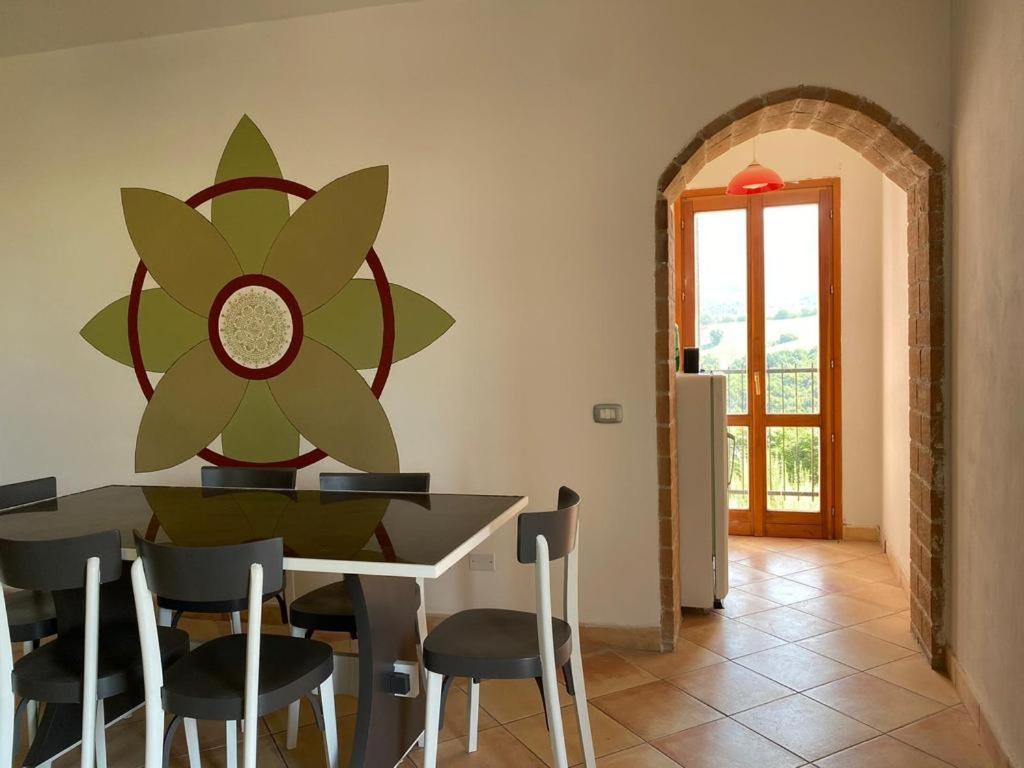 une salle à manger avec une table, des chaises et une fleur sur le mur dans l'établissement Tenuta Frasassi, à Collegiglioni
