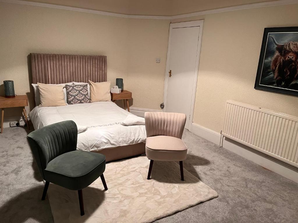 een slaapkamer met een bed, een stoel en een tafel bij Luxury Cosy Retreat Apt in Londen