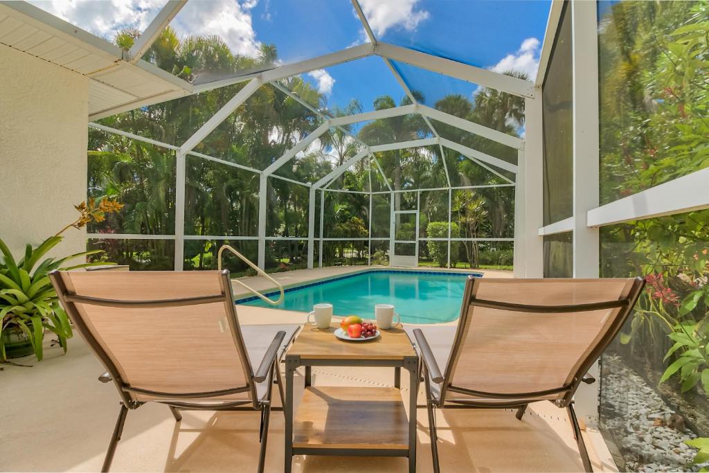 a conservatory with a table and chairs in front of a pool at Private Heated Pool & Beach House in Vero Beach
