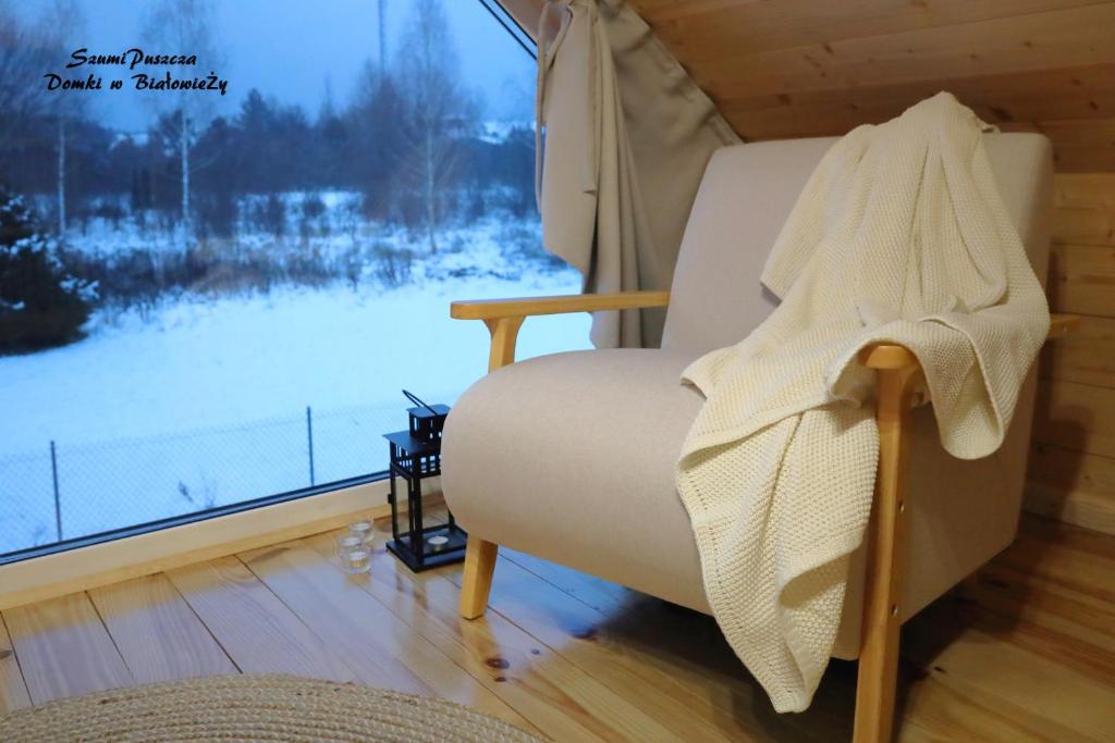 einen weißen Stuhl in einem Zimmer mit Fenster in der Unterkunft SzumiPuszcza - domki, sauna, jacuzzi in Białowieża