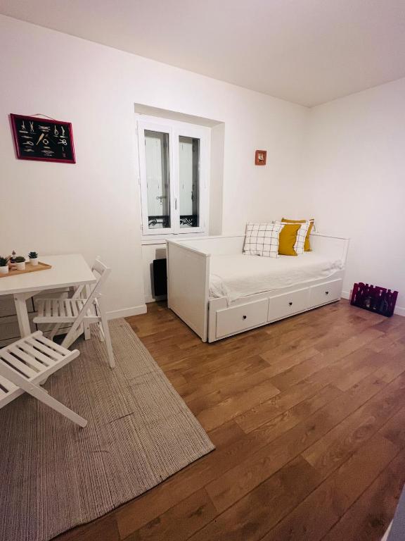 a white room with a bed and a table at Studio neuf au calme proche gare maritime - 7 min in Nantes
