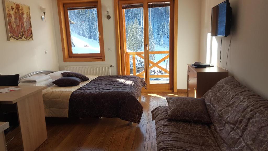 Un dormitorio con una cama y un sofá y una ventana. en Apartman 151 U u Aparthotelu Vučko Jahorina - private host, en Jahorina