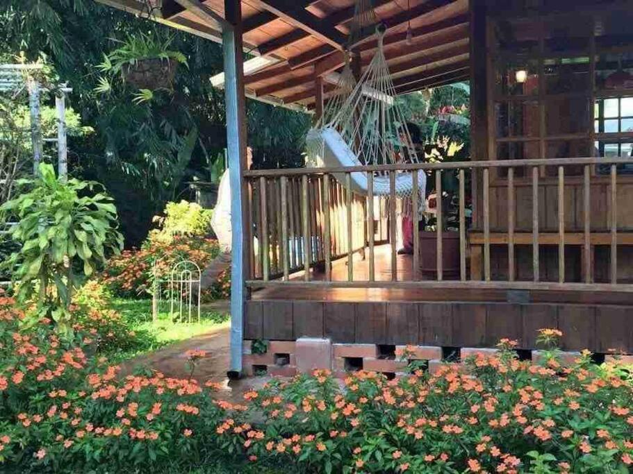 a porch of a house with flowers at Wooden House Mindo - Casa de Las Nevadas in Mindo