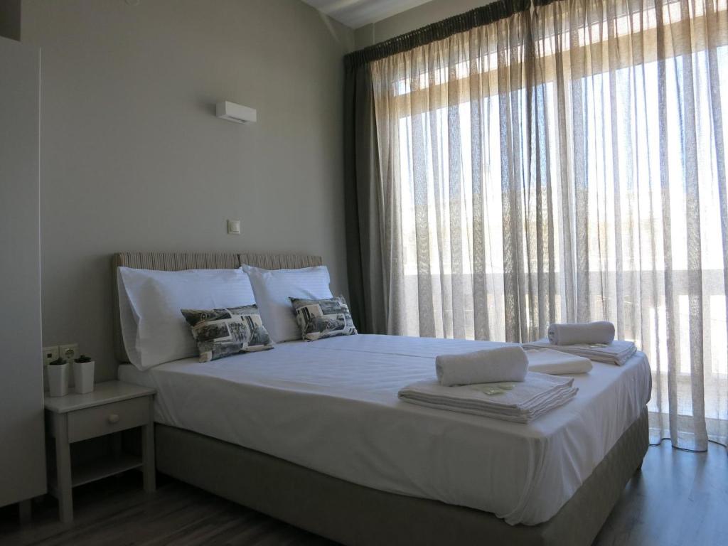 sypialnia z dużym łóżkiem i dużym oknem w obiekcie Pantheon Aparthotel w Chanii
