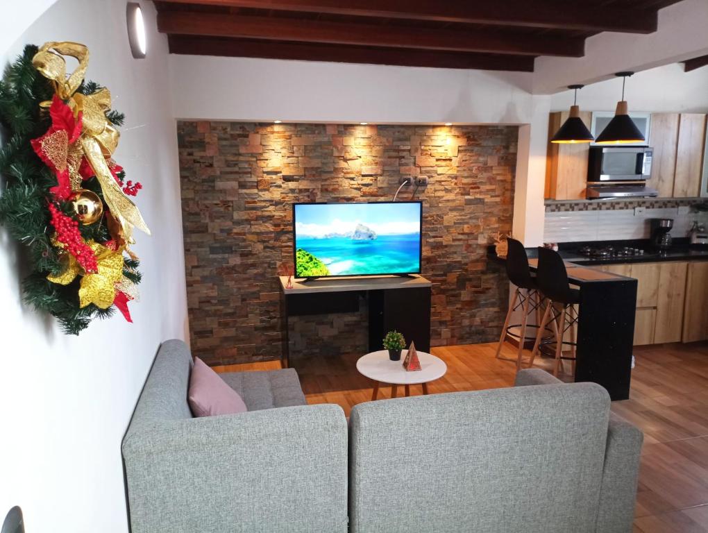 a living room with a television on a brick wall at Hermoso apartamento en Medellín in Medellín