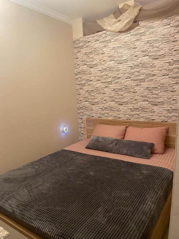 a bed with two pillows and a brick wall at AJ Apartment 2, Santa Marina Holiday Village, Sozopol in Sozopol