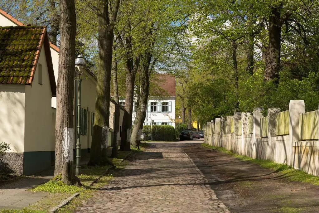 a road with a fence and a house and trees at Ferienhaus am Wasser - citynah in Berlin